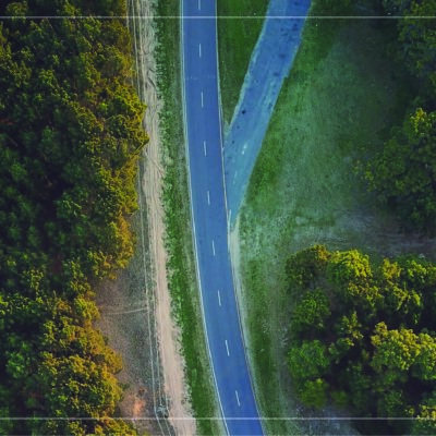 a drone photograph from above of a multi-lane highway running through woods