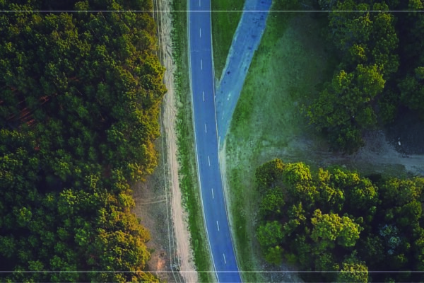 a drone photograph from above of a multi-lane highway running through woods